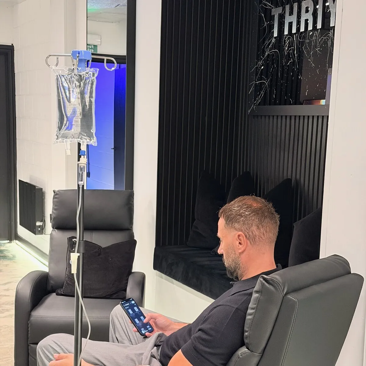 High-dose NAD+ IV in Manchester: a client relaxes in a lounge chair beside an IV drip at Thriyv